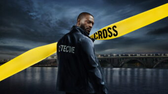 Alex Cross interprété par Aldis Hodge dans la série Cross sur Prime Video, devant un pont nocturne avec ruban jaune d’enquête