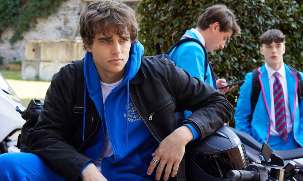 James assis sur une moto devant une école internationale à Milan dans Love Me Love Me sur Prime Video