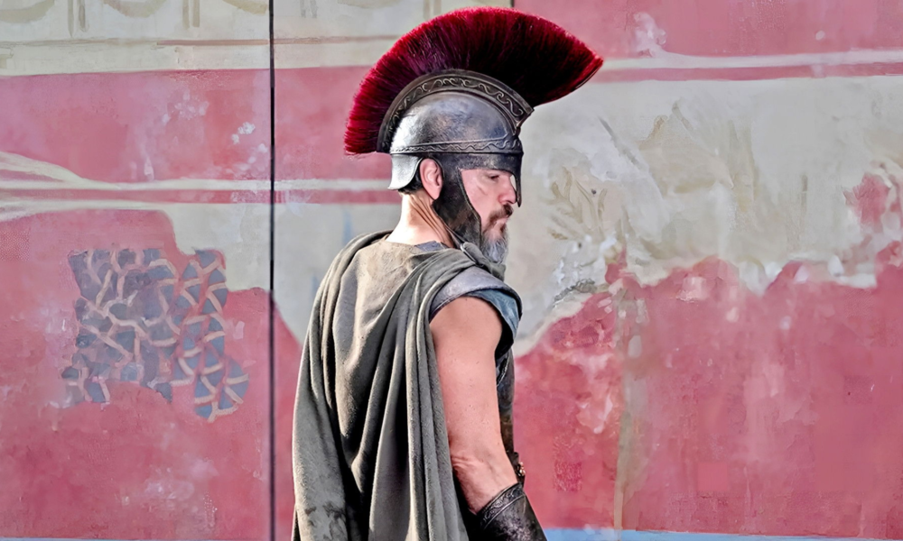 Soldat grec en armure avec casque à crête rouge pendant la guerre de Troie dans L’Odyssée de Christopher Nolan
