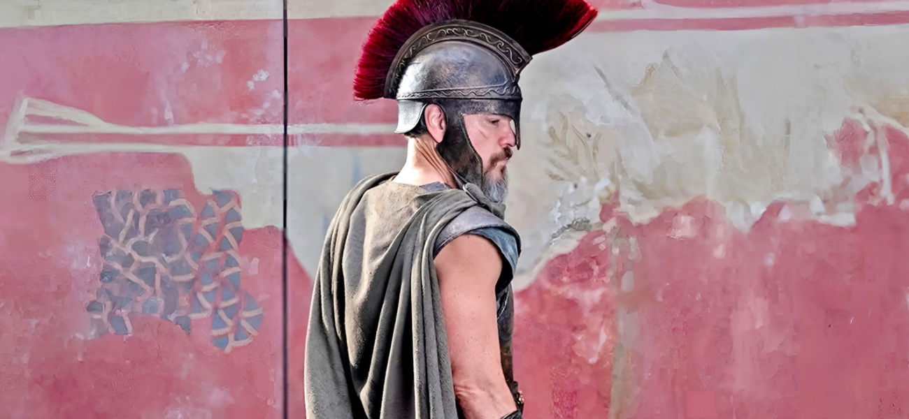 Soldat grec en armure avec casque à crête rouge pendant la guerre de Troie dans L’Odyssée de Christopher Nolan