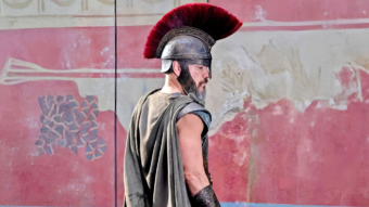 Soldat grec en armure avec casque à crête rouge pendant la guerre de Troie dans L’Odyssée de Christopher Nolan