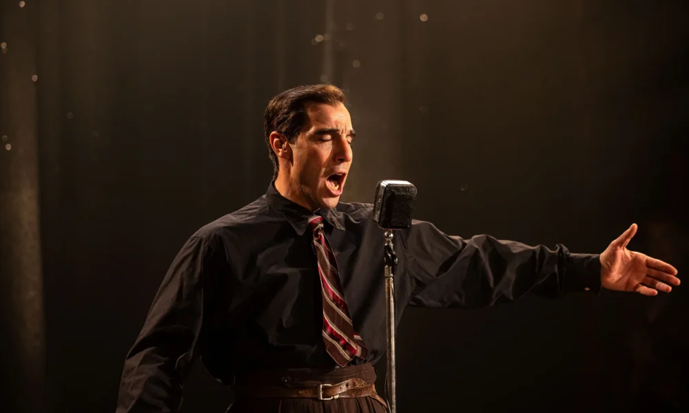 Tahar Rahim incarnant Charles Aznavour sur scène dans le film Monsieur Aznavour