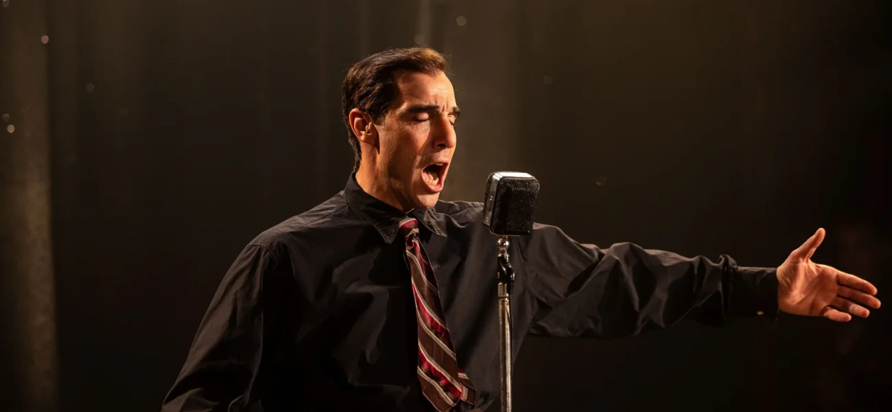 Tahar Rahim incarnant Charles Aznavour sur scène dans le film Monsieur Aznavour
