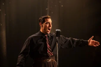 Tahar Rahim incarnant Charles Aznavour sur scène dans le film Monsieur Aznavour