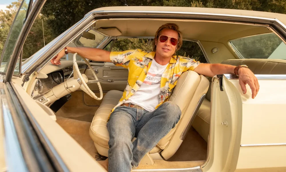 Brad Pitt dans le rôle de Cliff Booth, assis dans une voiture vintage, dans The Adventures of Cliff Booth