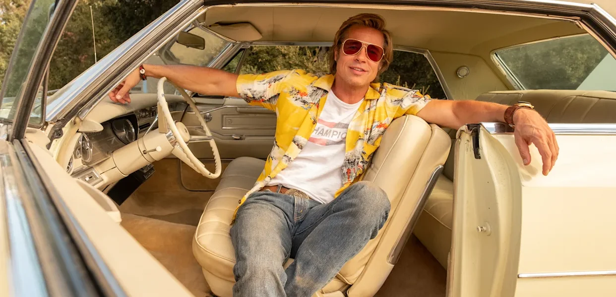 Brad Pitt dans le rôle de Cliff Booth, assis dans une voiture vintage, dans The Adventures of Cliff Booth