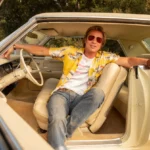 Brad Pitt dans le rôle de Cliff Booth, assis dans une voiture vintage, dans The Adventures of Cliff Booth