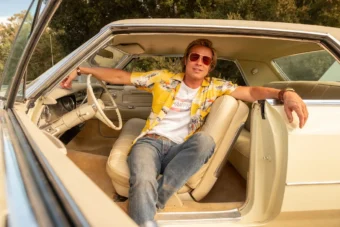 Brad Pitt dans le rôle de Cliff Booth, assis dans une voiture vintage, dans The Adventures of Cliff Booth