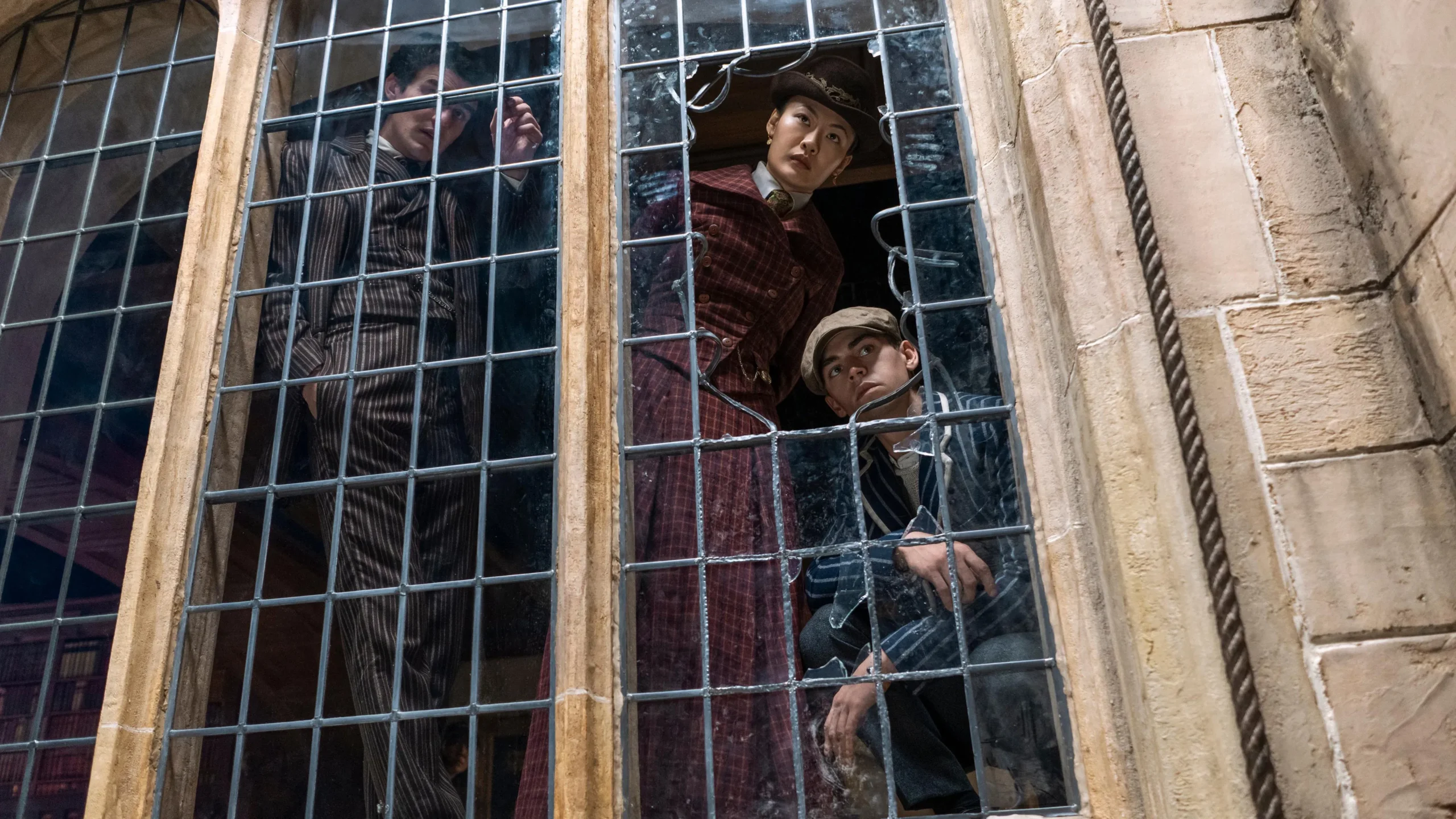 Scène de la série Young Sherlock montrant de jeunes personnages observant Oxford depuis une fenêtre grillagée.